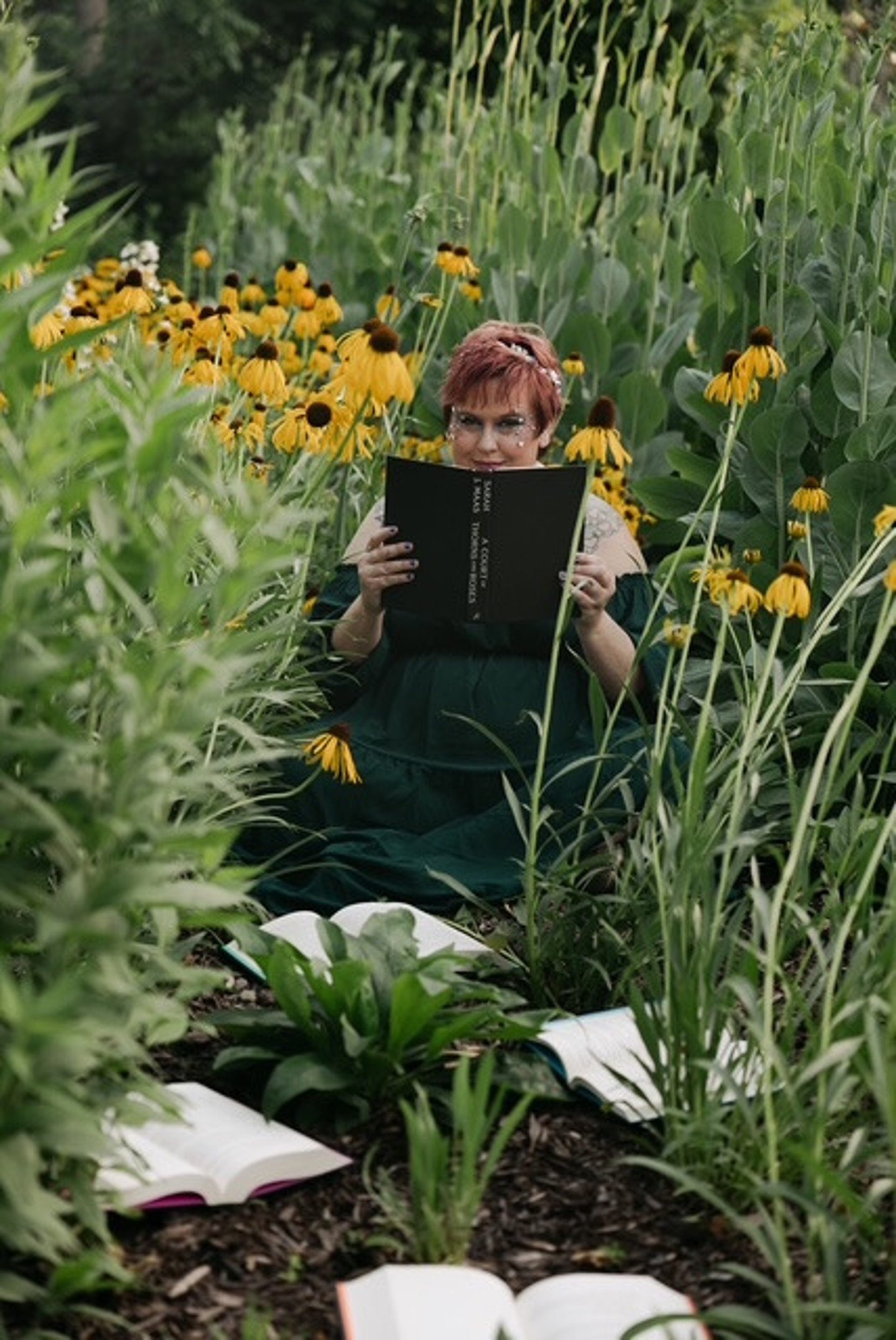 Fantasy-styled reader seated among flowers with an open book