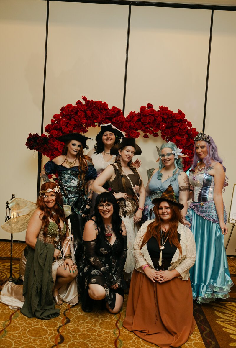 A group of costumed guests posing at the red rose wall at Phantoms of the Deep