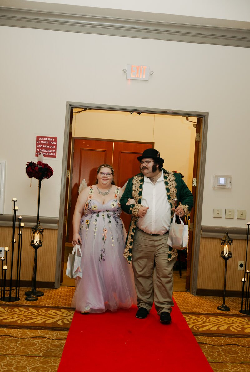 Two costumed guests walking arm in arm along a red carpet at Phantoms of the Deep