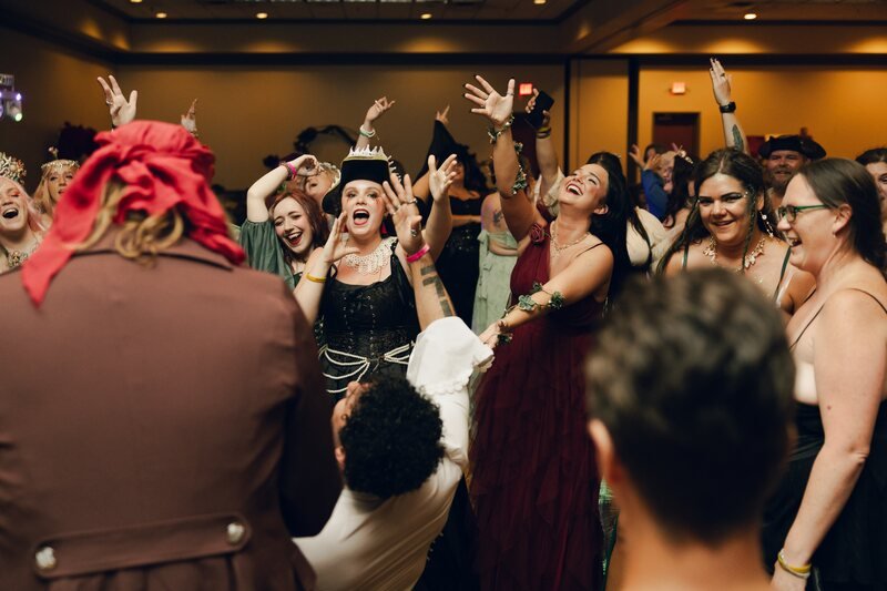 A crowd of costumed guests cheering at the Saturday night ball
