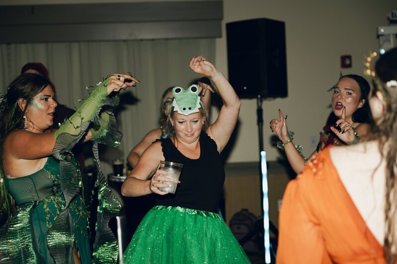 Costumed guests dancing, including one in a bright green creature hat, at Phantoms of the Deep